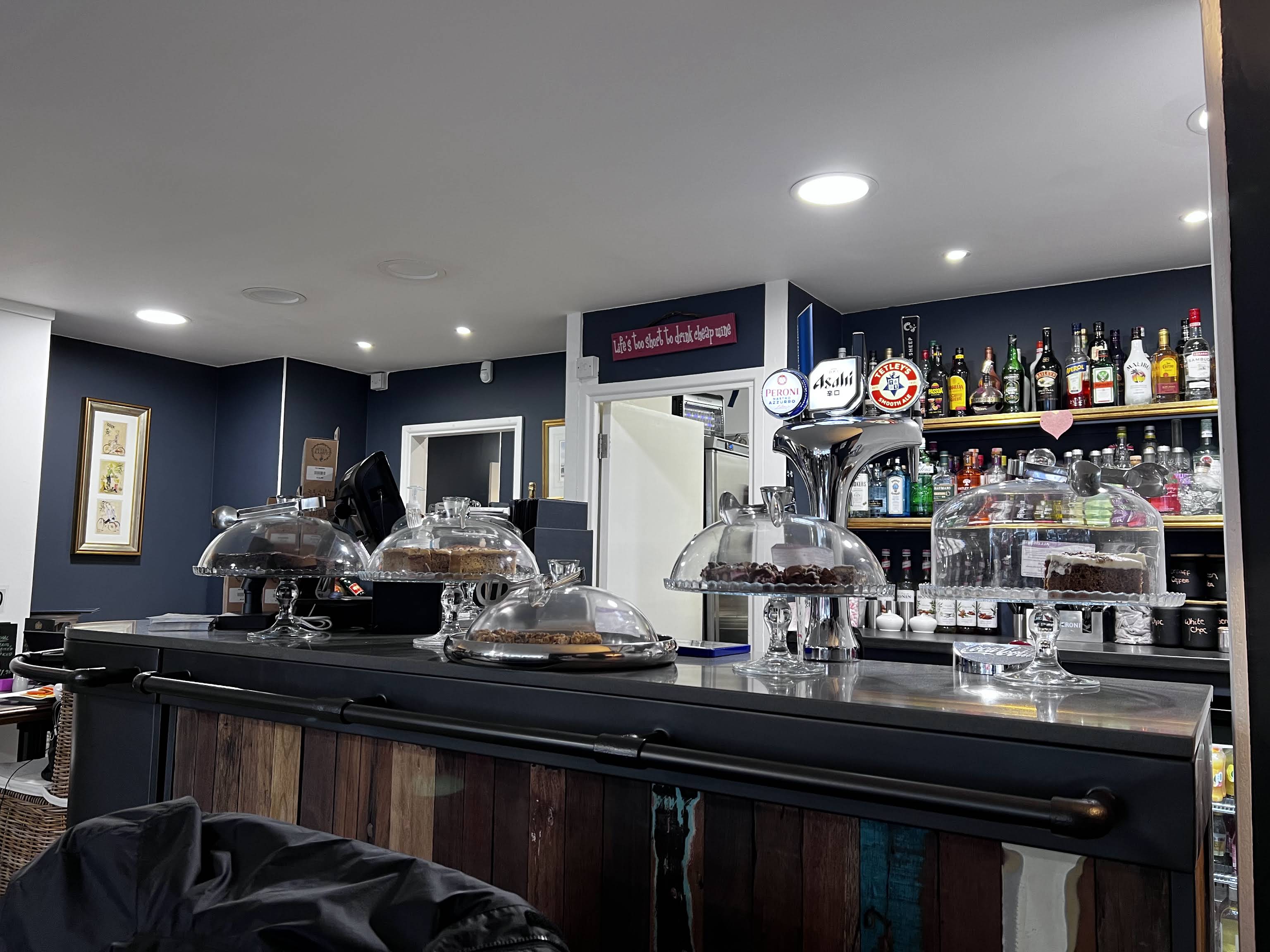 Utopia’s dark-blue café bar, wooden counter, cake display and drinks shelves